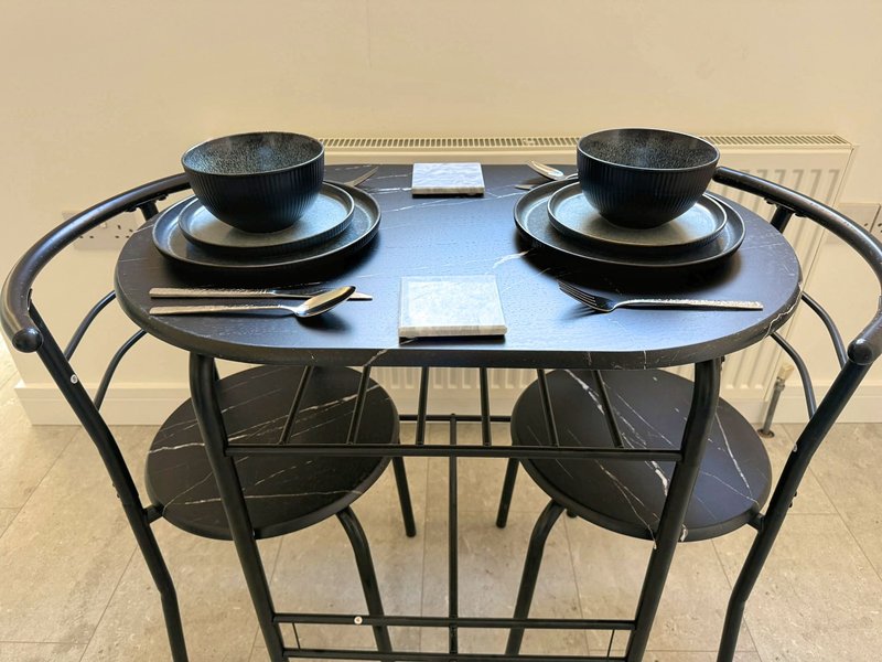 Dining table set for two with black bowls, plates, cutlery and napkins