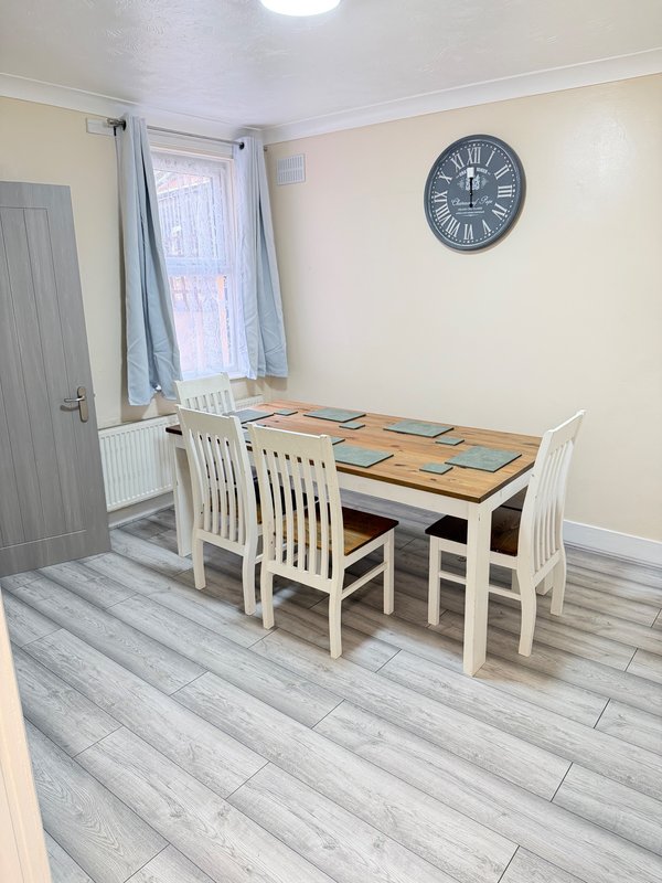 Dining room with white table, chairs, window, and wall clock