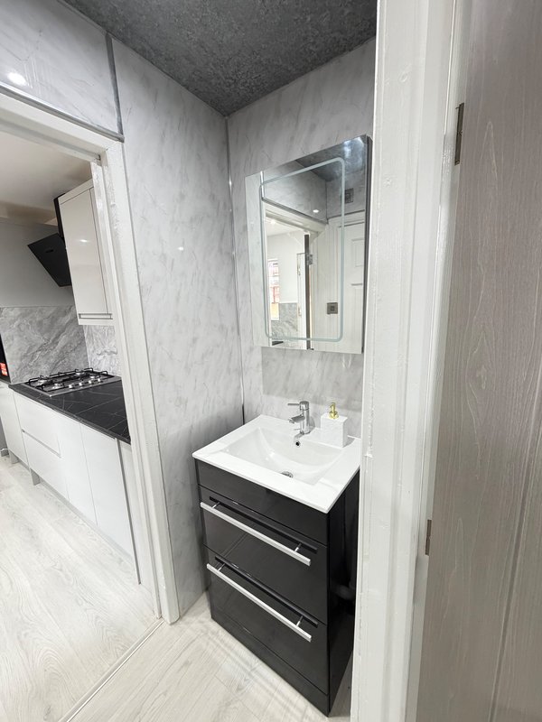 Modern bathroom with black vanity unit, white sink, and mirror above