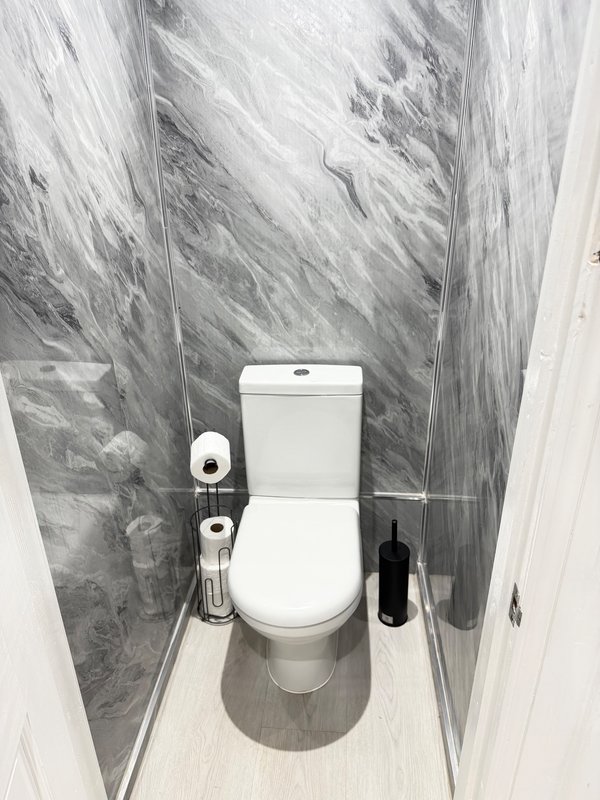 Modern bathroom with white toilet, grey marble-effect wall tiles and light flooring