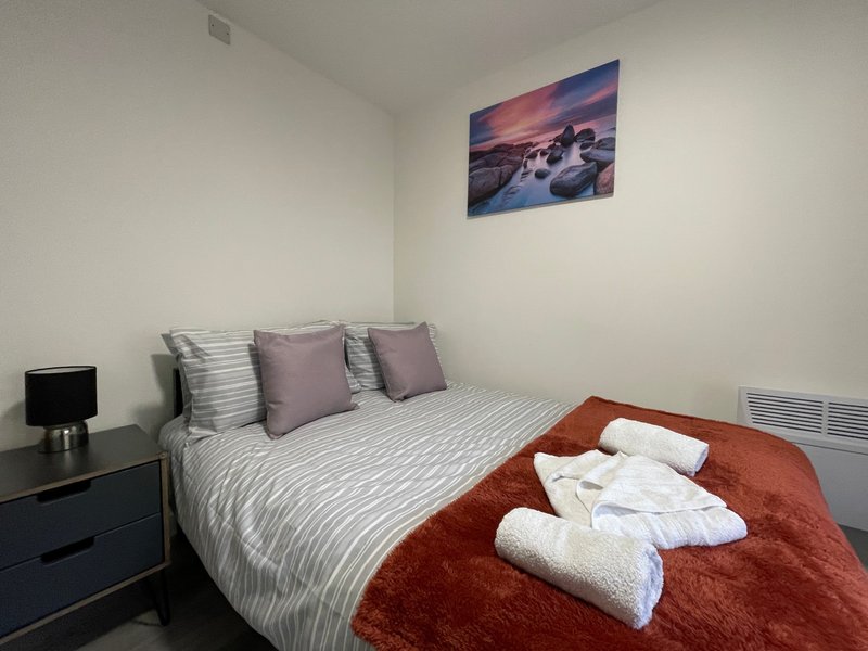 Modern bedroom with double bed, striped bedding, decorative pillows and folded towels