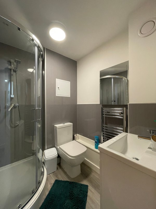 Modern bathroom with shower cubicle, toilet, white sink and heated towel rail