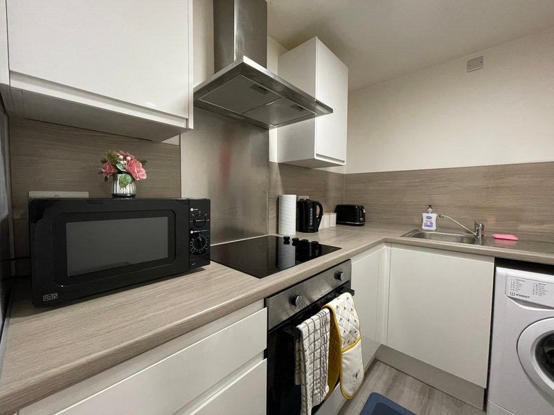 Modern kitchen with white cabinetry, stainless steel appliances, microwave, and flowers in vase
