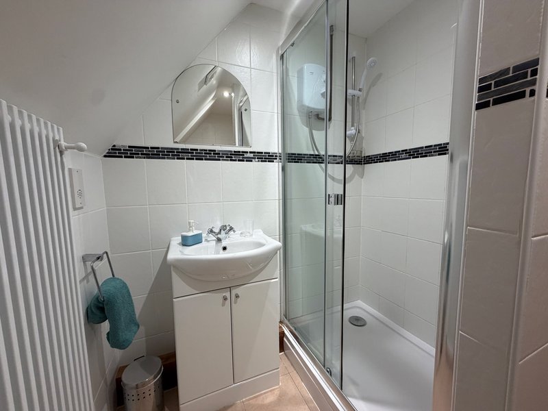 Modern bathroom with white vanity, mirror, shower enclosure and heated towel rail