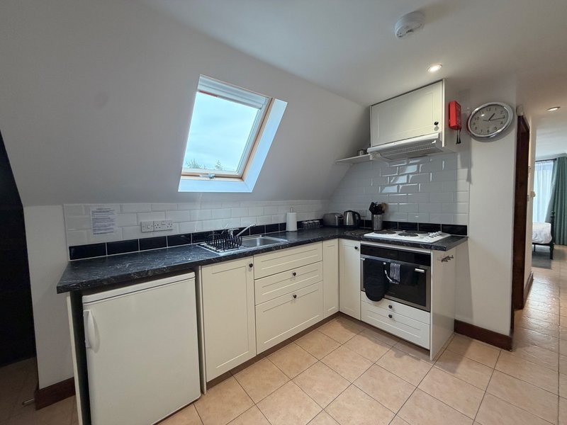 Modern kitchen with cream cabinets, black countertop, white range cooker and skylight window
