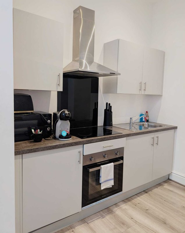 Modern white kitchen with stainless steel hood, black oven, granite countertop and wall cabinets