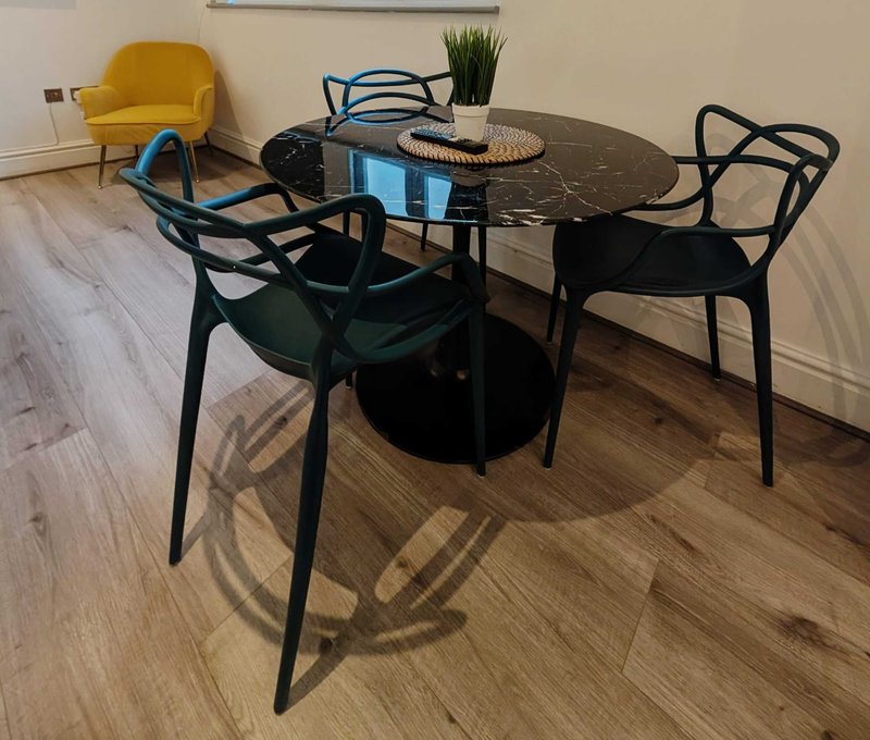 Dining area with black round table, modern chairs, potted plant and yellow accent chair