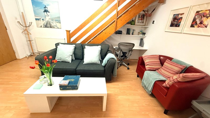 Open-plan ground floor living room with a sofa bed, sofa, white coffee table and framed wall art