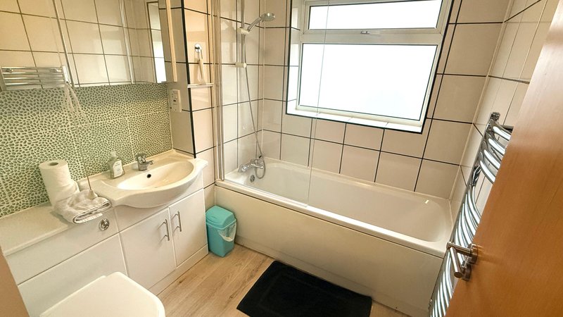 Modern bathroom with white suite, tiled shower enclosure and green tile accent wall