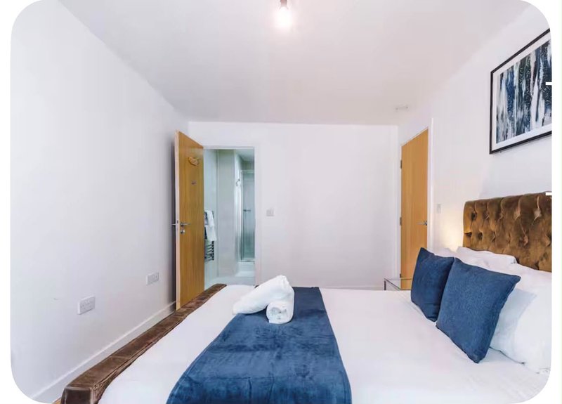 Modern bedroom with double bed, blue bedding, white pillows, and wooden doors