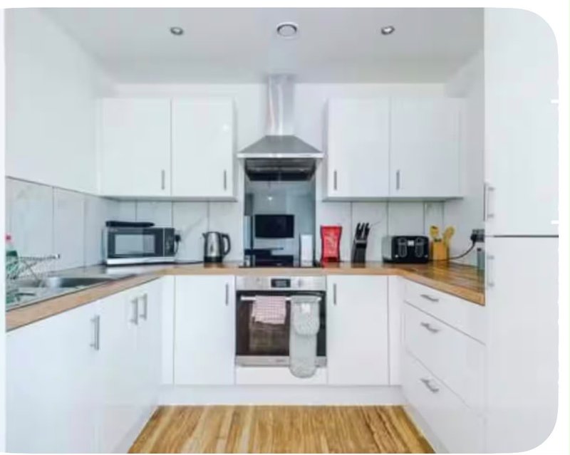 Modern white kitchen with wooden worktops, stainless steel appliances and island unit