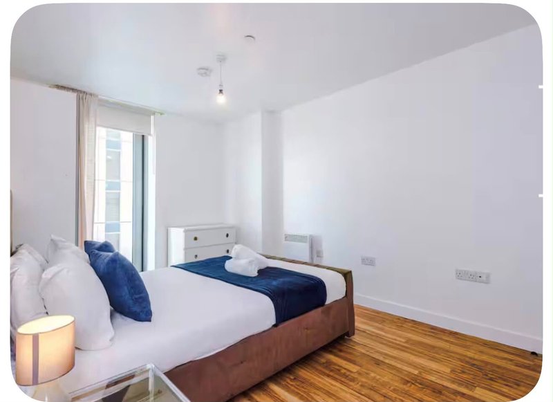 Bright modern bedroom with double bed, wooden floor, blue bedding and access to balcony