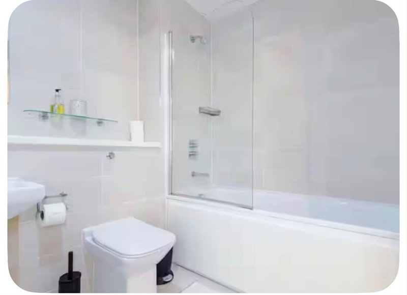 Modern white bathroom with toilet, sink, bathtub and glass shower enclosure