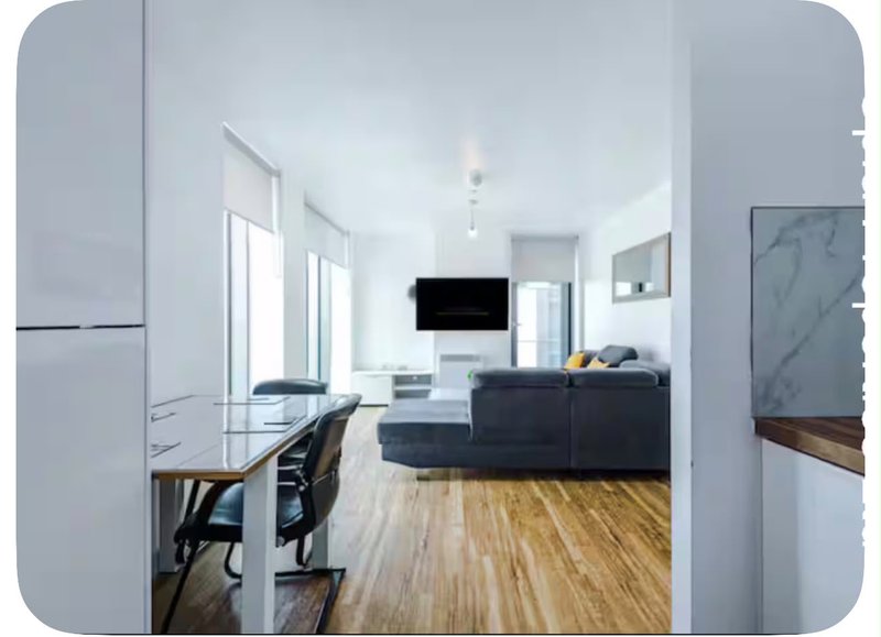 Modern open-plan living space with kitchen, dining area, sofa and wall-mounted TV
