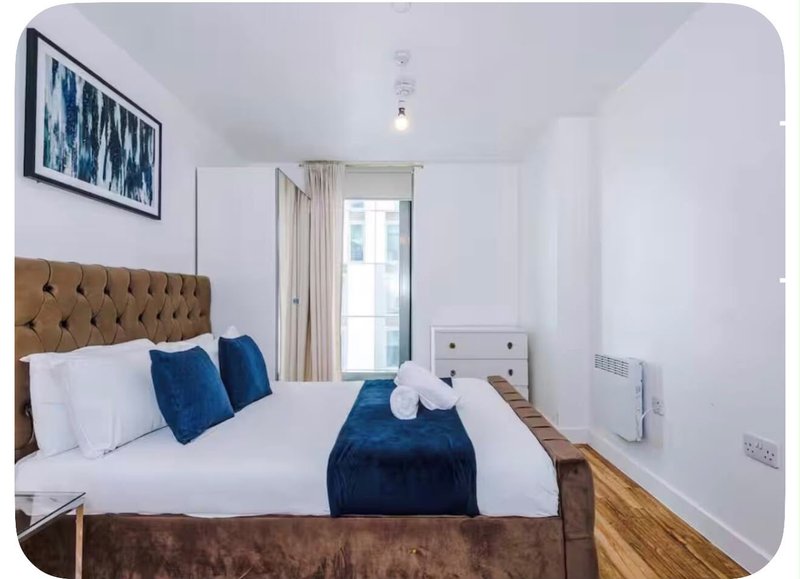 Modern bedroom with double bed, tufted headboard, blue cushions and white bedding