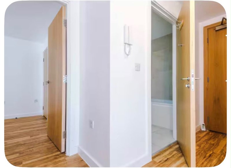 Bright hallway with wooden doors, laminate flooring, and shower enclosure visible