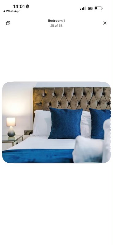 Bedroom with upholstered headboard, blue cushions, white pillows and bedside lamp