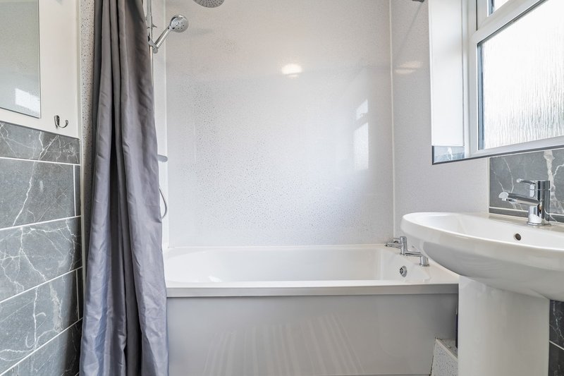 Modern bathroom with bathtub, shower enclosure, pedestal sink and grey tile walls