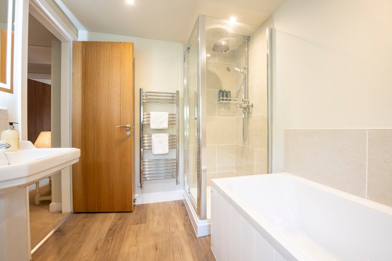 Modern bathroom with freestanding bathtub, walk-in shower, wooden door and heated towel rail