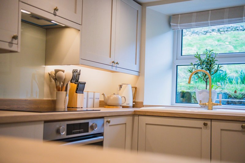 Modern kitchen with cream cabinets, wooden countertop, stainless steel oven and window with garden view