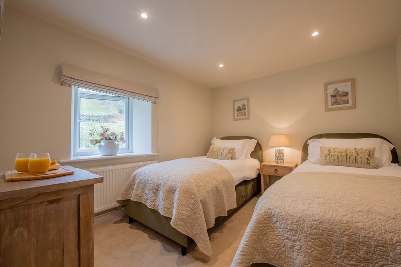 Bright twin bedroom with two single beds, wooden furniture, window with countryside view