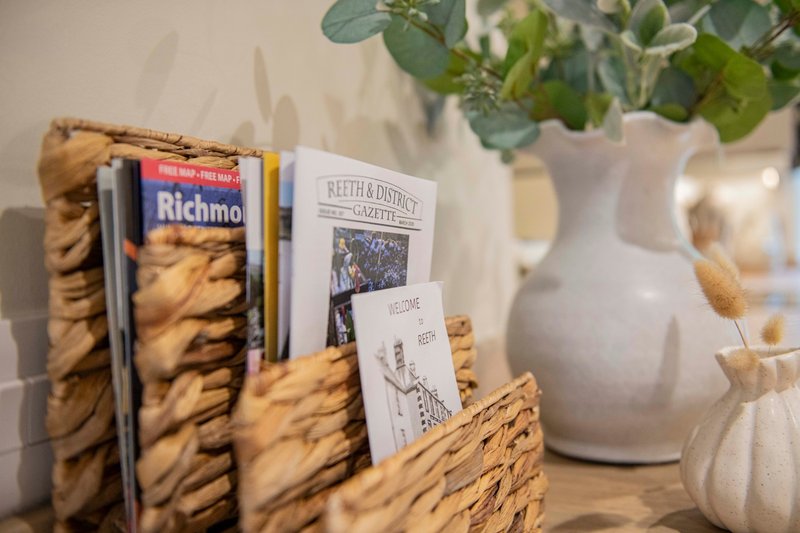 Kitchen shelf with packaged biscuits, decorative magazines, potted eucalyptus plant and white ceramic vase