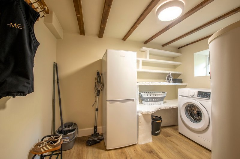 Utility room with washing machine, refrigerator, shelving and cleaning supplies