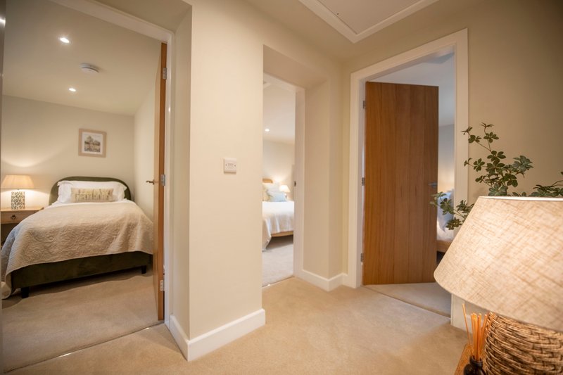 Hallway with cream carpeting, wooden doors, and views into multiple bedrooms