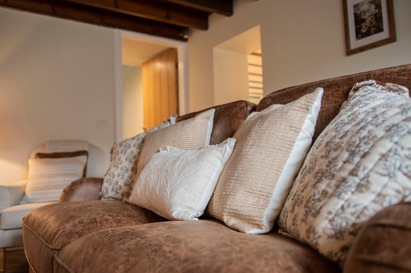 Brown sofa with patterned and textured cushions, open doorway to adjacent room