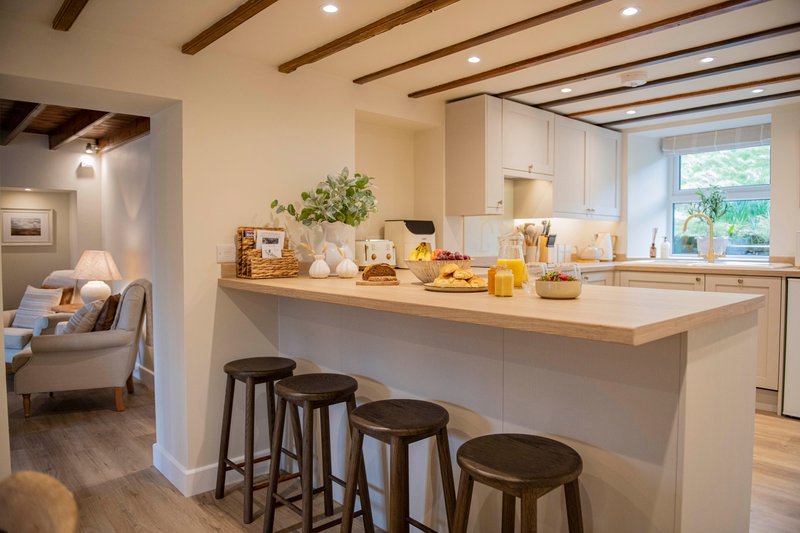 Modern kitchen with white island, bar stools, and countertop accessories near windows