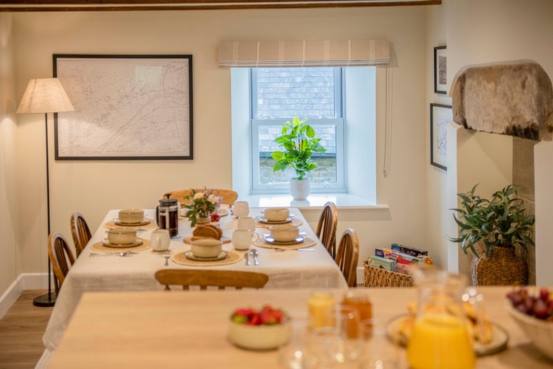 Dining room with set table, chairs, window with plant, and floor lamp