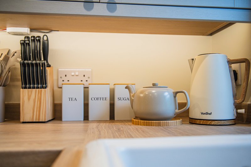 Kitchen shelf with wooden knife block, tea and coffee canisters, kettle and kitchen utensils