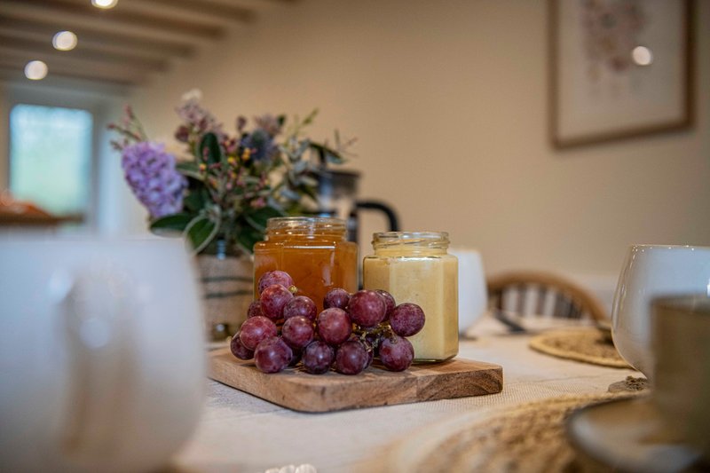Kitchen counter with fresh grapes, preserves in jars, and purple flowers in vase
