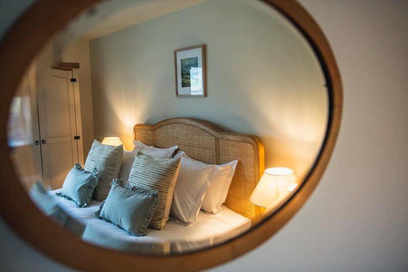 Cozy bedroom with double bed, rattan headboard, striped pillows and warm lighting
