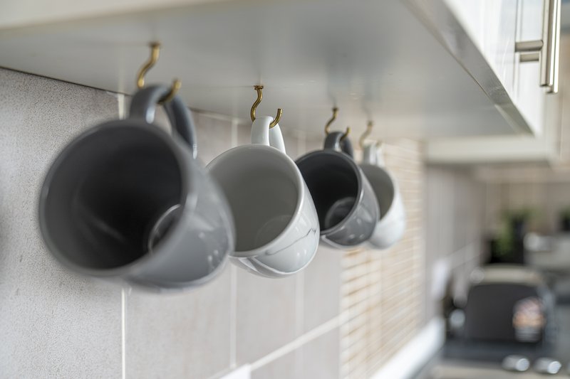 Kitchen detail showing mugs hanging on hooks above counter