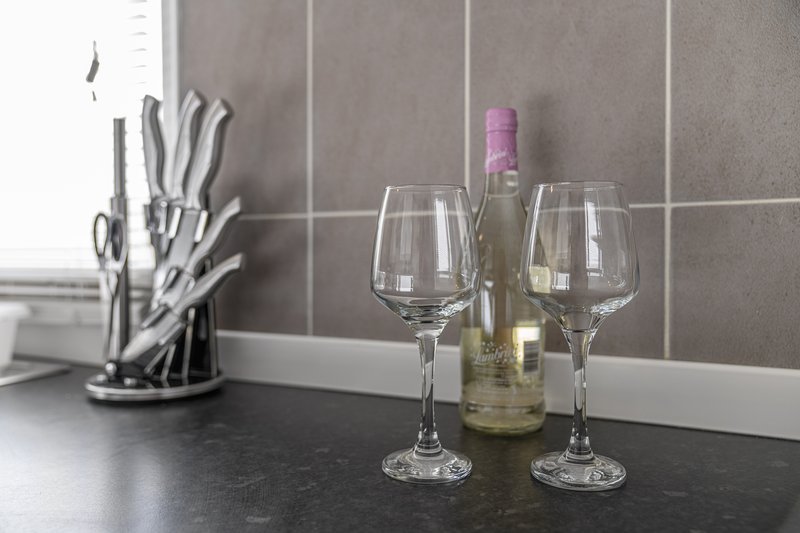 Kitchen counter with wine bottle, wine glasses, and knife block by tiled backsplash