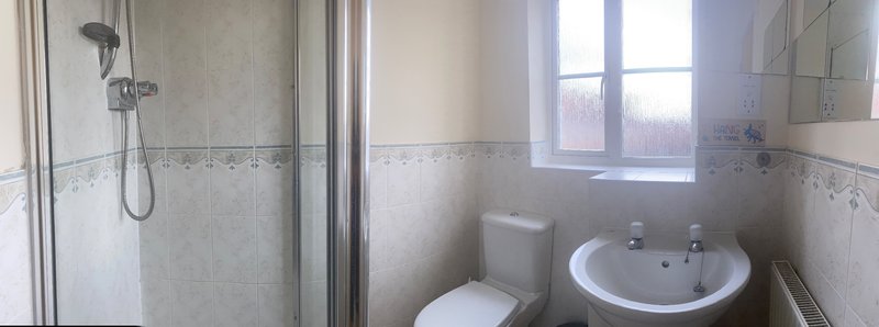 Bathroom with shower enclosure, toilet, sink and window with natural light