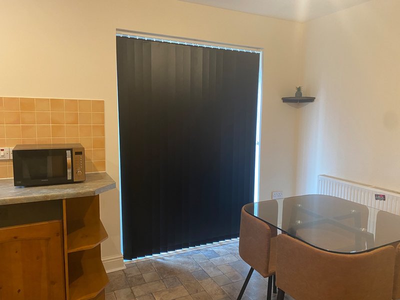 Kitchen with microwave, dining table, and french doors with black vertical blackout blinds
