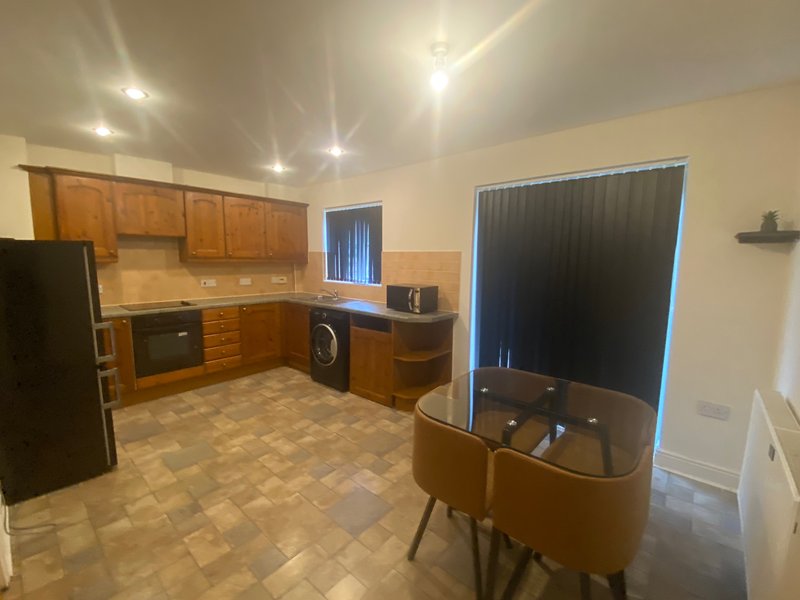 Kitchen-diner with wooden cabinets, black appliances, dining table and tiled flooring
