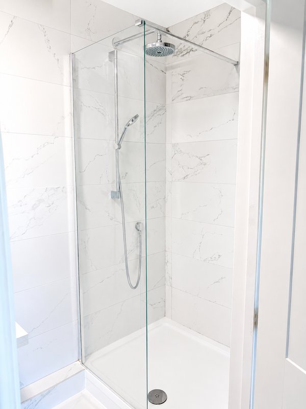 Modern bathroom shower enclosure with marble-effect tiling and rainfall showerhead