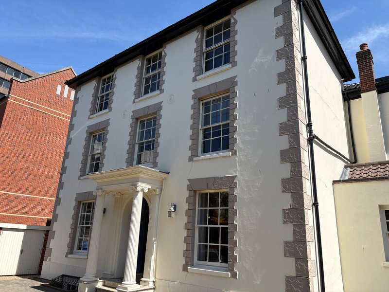 Stone-fronted period building with multi-pane sash windows and contemporary entrance porch