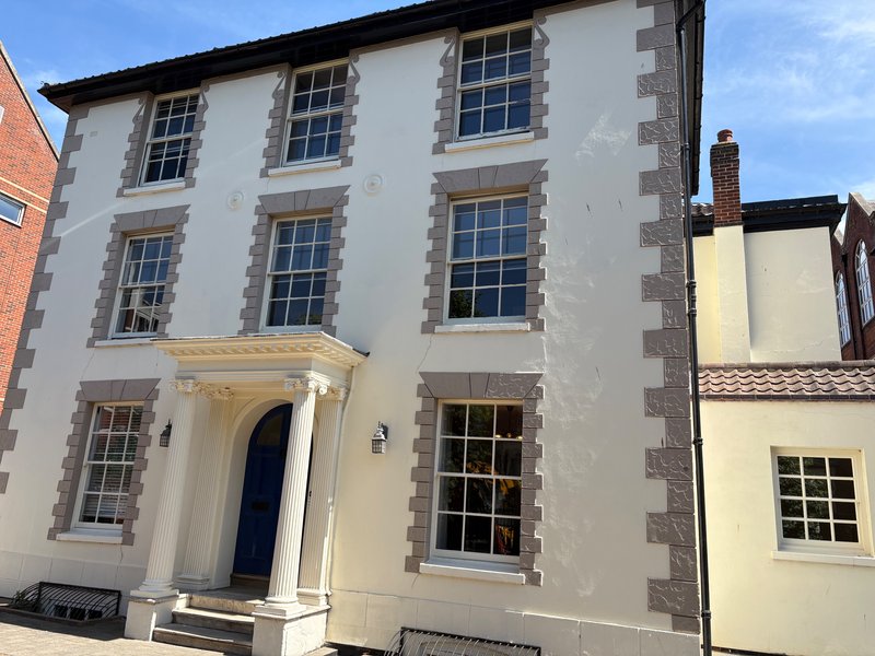 Cream-rendered Georgian townhouse with sash windows and dark blue entrance door