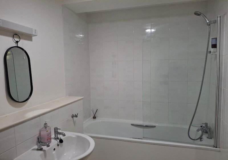 Clean white bathroom with sink, mirror, bathtub and glass shower enclosure