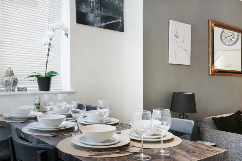Dining table set for two with white plates, glasses, and place settings indoors