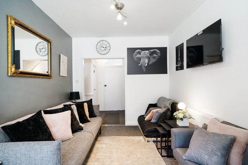 Modern living room with grey sofa, armchair, wall art, and mounted television