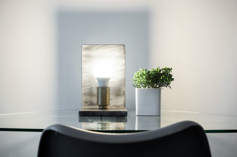 Modern desk with lamp, potted plant, and framed mirror against blue wall