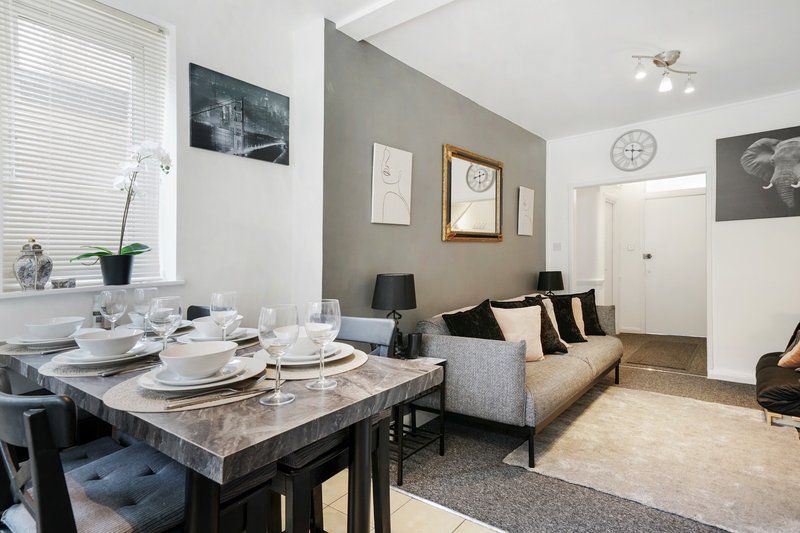 Open-plan living and dining area with grey sofa, dining table, and kitchen visible