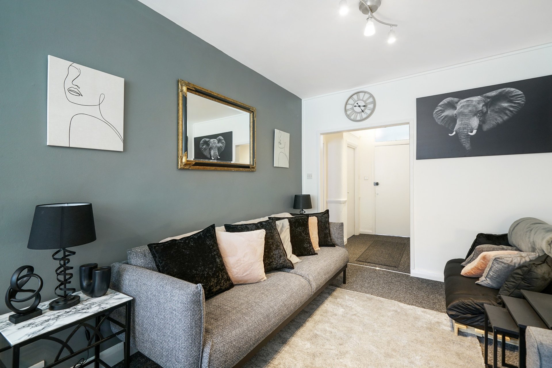 Living room with gray sofa, teal accent wall, framed artwork, and modern furnishings