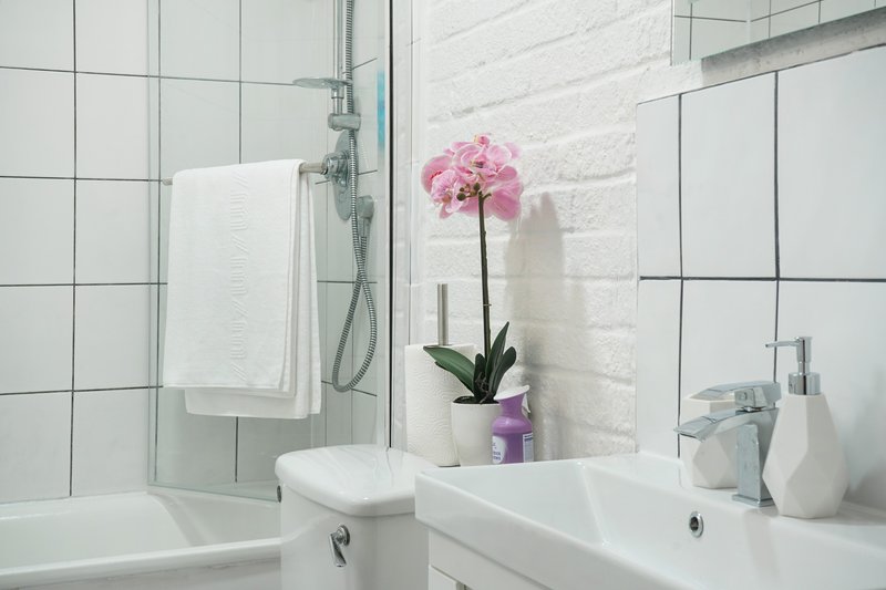 Modern white bathroom with sink, toilet, bathtub and pink flower decoration