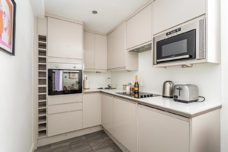 Modern white kitchen with built-in appliances, microwave, kettle and countertop accessories